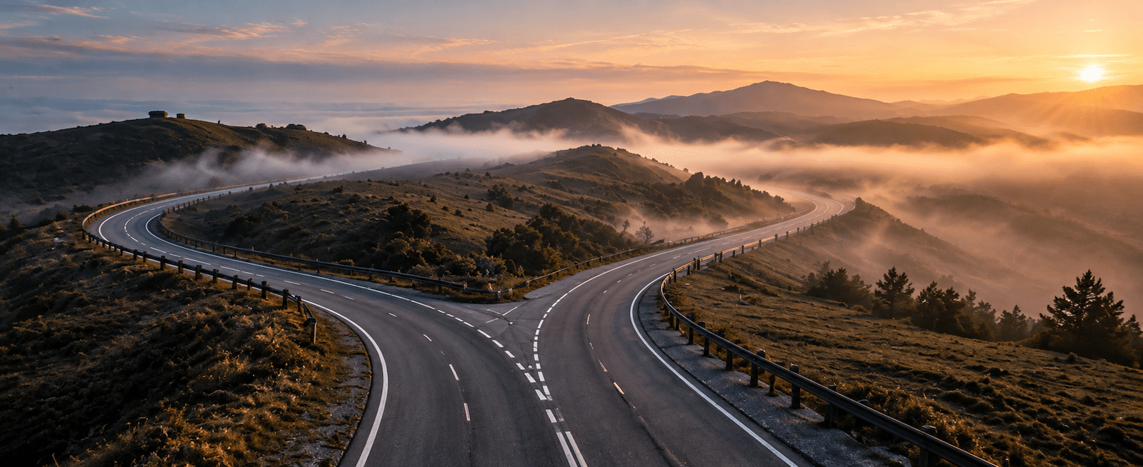 A road forking into two paths through misty hills at sunrise